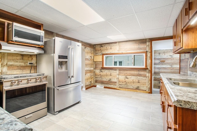 8464 E Michigan Ave, Galesburg, MI 49053 - kitchen with appliances with stainless steel finishes, brown cabinetry, a paneled ceiling, wooden walls, and ventilation hood
