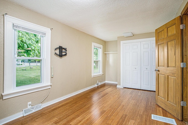 8464 E Michigan Ave, Galesburg, MI 49053 - unfurnished bedroom featuring light wood-style flooring, a closet, and a textured ceiling