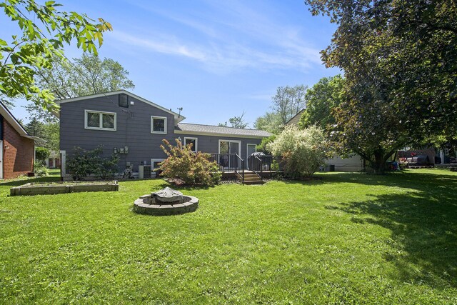 8683 Hemlock Ct, Ypsilanti, MI 48198 - rear view of house with an outdoor fire pit, a wooden deck, and a yard