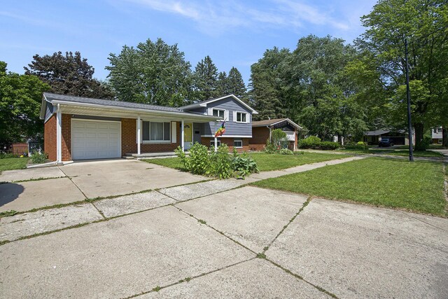 8683 Hemlock Ct, Ypsilanti, MI 48198 - tri-level home featuring a garage, brick siding, concrete driveway, and a front lawn