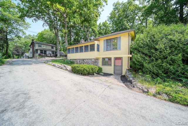 5027 Belemere Ct, Manitou Beach, MI 49253 - view of front of house featuring stone siding and a sunroom