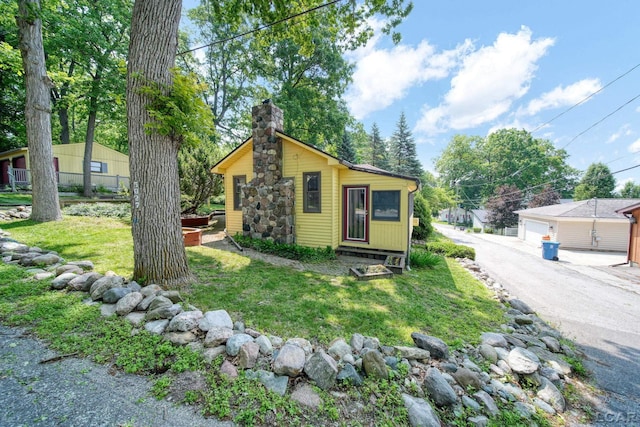 5027 Belemere Ct, Manitou Beach, MI 49253 - view of front facade featuring a chimney, a front yard, an outdoor structure, and a detached garage