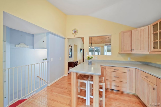 5027 Belemere Ct, Manitou Beach, MI 49253 - kitchen featuring light brown cabinets, vaulted ceiling, light wood-style floors, light countertops, and glass insert cabinets