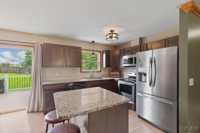 7673 Dalton Rd, Onsted, MI 49265 - kitchen featuring stainless steel appliances, a kitchen breakfast bar, dark brown cabinets, light wood-type flooring, and light stone countertops