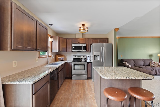 7673 Dalton Rd, Onsted, MI 49265 - kitchen featuring appliances with stainless steel finishes, light wood-style flooring, a kitchen breakfast bar, open floor plan, and light stone countertops