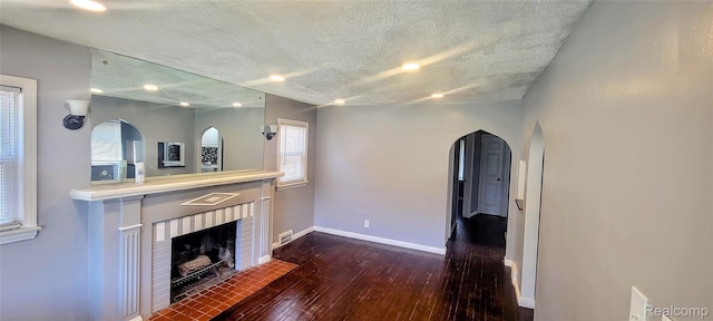 18978 Indiana St, Detroit, MI 48221 - unfurnished living room featuring hardwood / wood-style flooring, a textured ceiling, a fireplace, arched walkways, and recessed lighting