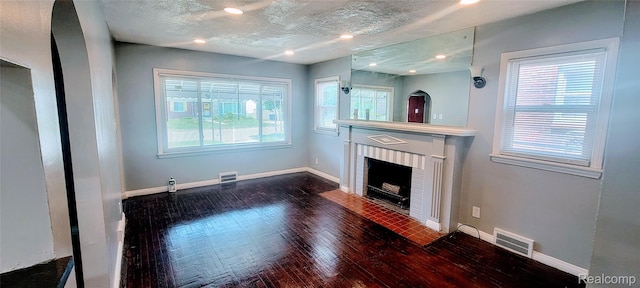 18978 Indiana St, Detroit, MI 48221 - unfurnished living room featuring dark wood-style floors, a brick fireplace, a textured ceiling, and recessed lighting