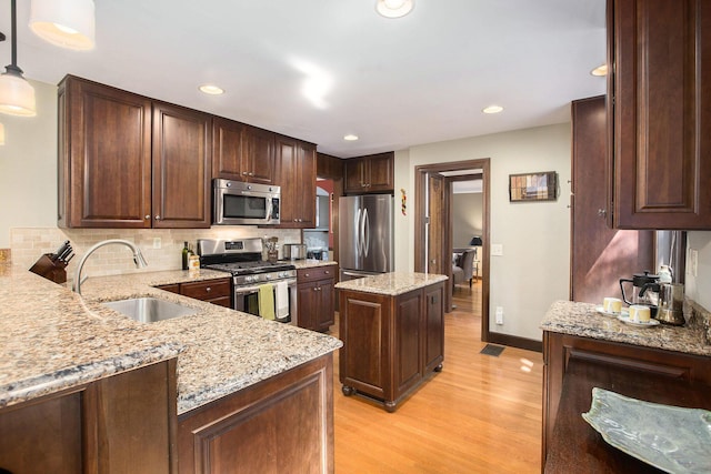 1506 Shadford Rd, Ann Arbor, MI 48104 - kitchen featuring appliances with stainless steel finishes, light wood-style flooring, light stone countertops, decorative backsplash, and pendant lighting