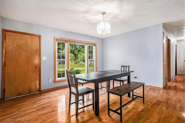 201 Beaumont Dr, Battle Creek, MI 49014 - dining area with a chandelier, light wood finished floors, and a textured ceiling