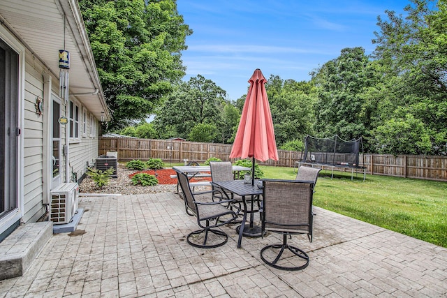 201 Beaumont Dr, Battle Creek, MI 49014 - fenced backyard with a trampoline, a patio, outdoor dining area, and view of wooded area