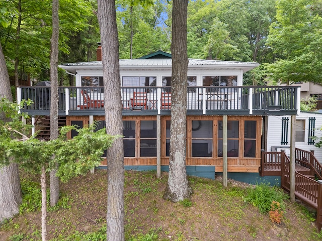 3184 N Lakeshore Dr, Hillsdale, MI 49242 - back of property with stairway, a sunroom, a wooden deck, a chimney, and a metal roof