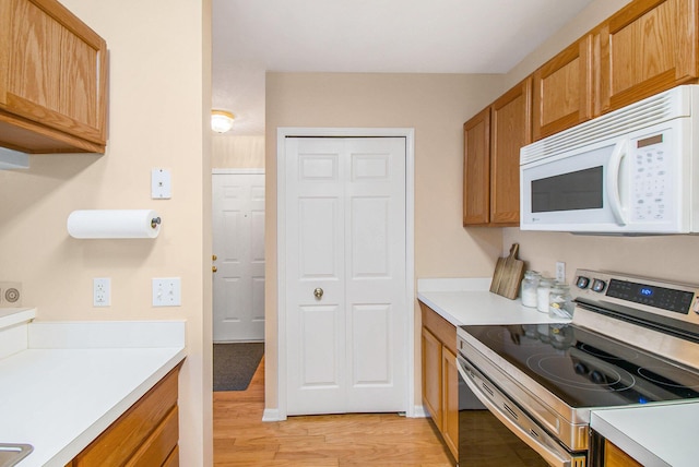 749 W Barrington Cir, Jackson, MI 49203 - kitchen featuring stainless steel range with electric stovetop, white microwave, light wood-style floors, light countertops, and brown cabinetry