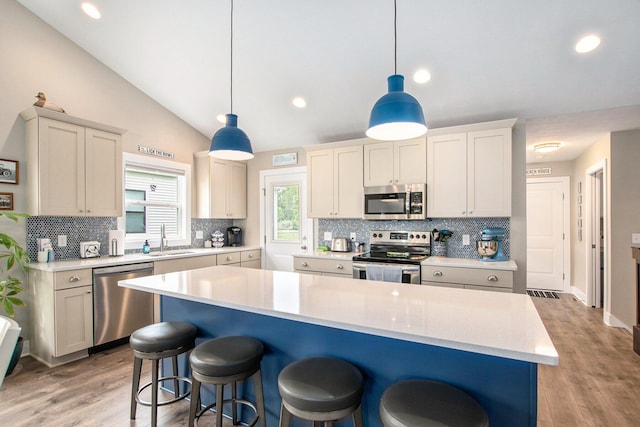 964 Everett Pkwy, South Haven, MI 49090 - kitchen with appliances with stainless steel finishes, decorative backsplash, light countertops, a kitchen bar, and vaulted ceiling