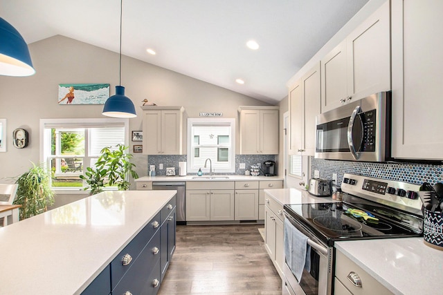 964 Everett Pkwy, South Haven, MI 49090 - kitchen with stainless steel appliances, vaulted ceiling, light countertops, pendant lighting, and tasteful backsplash