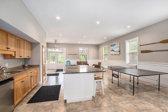 964 Everett Pkwy, South Haven, MI 49090 - kitchen with stainless steel dishwasher, a center island, a wainscoted wall, dark stone countertops, and a breakfast bar area