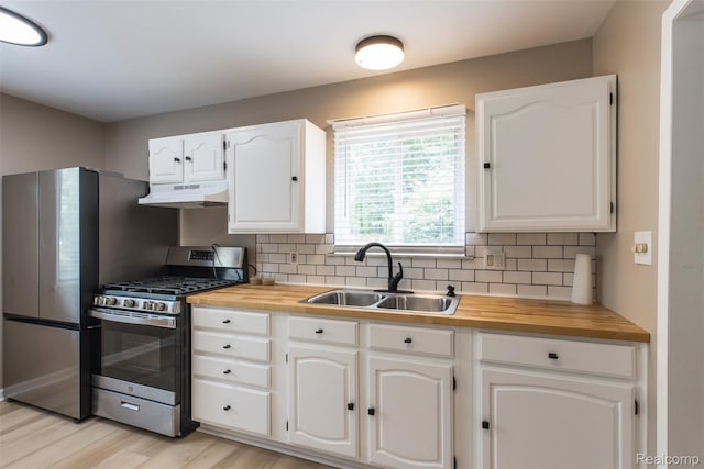 6580 Troy St, Southgate, MI 48180 - kitchen with appliances with stainless steel finishes, under cabinet range hood, butcher block counters, tasteful backsplash, and white cabinetry