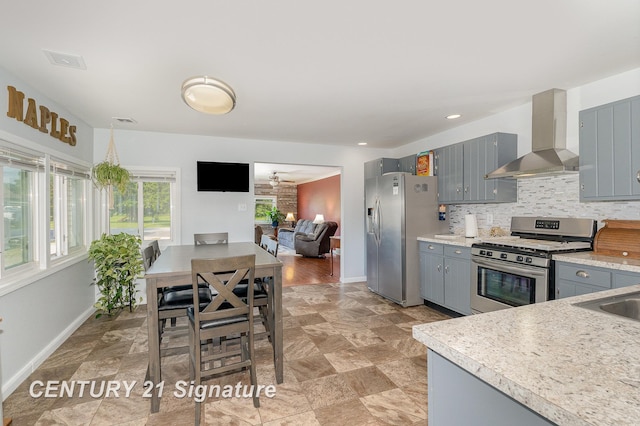 2942 Harrison St, Saginaw, MI 48604 - kitchen featuring wall chimney exhaust hood, appliances with stainless steel finishes, gray cabinets, light countertops, and tasteful backsplash