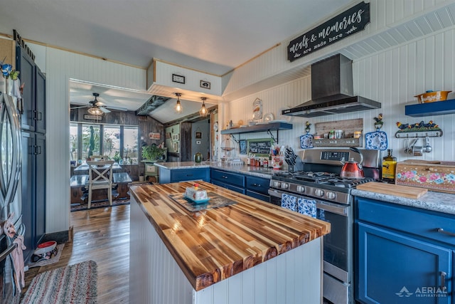 4441 Deckerville Rd, Lupton, MI 48635 - kitchen with wall chimney exhaust hood, butcher block counters, gas stove, blue cabinetry, and wood finished floors