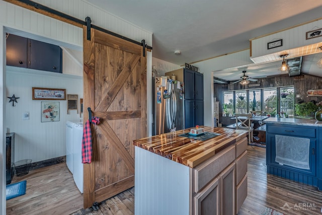 4441 Deckerville Rd, Lupton, MI 48635 - kitchen with a barn door, butcher block counters, independent washer and dryer, a ceiling fan, and wood finished floors