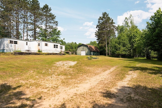 6038 SW Maple Hill Rd, Fife Lake, MI 49633 - view of grassy yard featuring a detached garage, an outbuilding, and driveway