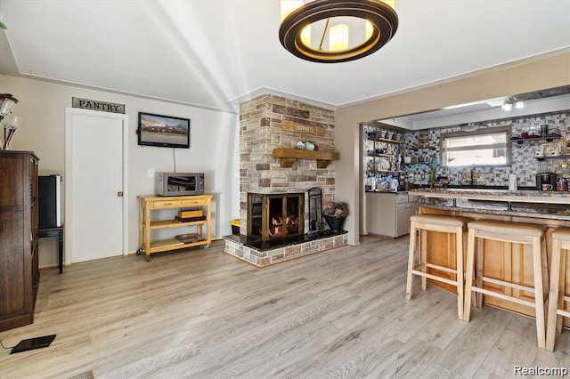 6003 Rolton Ct, Waterford, MI 48329 - living room featuring light wood-style flooring, a fireplace, and bar area
