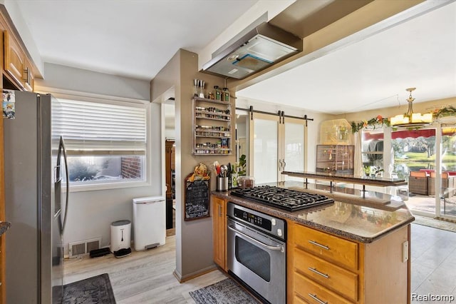 6003 Rolton Ct, Waterford, MI 48329 - kitchen with stainless steel appliances, dark stone counters, a barn door, brown cabinetry, and light wood-style flooring