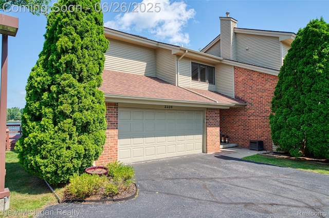 2226 Bowles St, Fenton, MI 48430 - view of front of house with brick siding, asphalt driveway, a garage, and a chimney