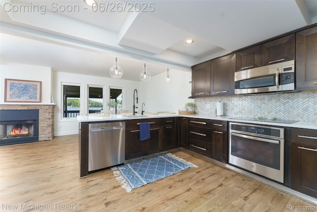 2226 Bowles St, Fenton, MI 48430 - kitchen with appliances with stainless steel finishes, light wood-style flooring, dark brown cabinetry, tasteful backsplash, and a peninsula