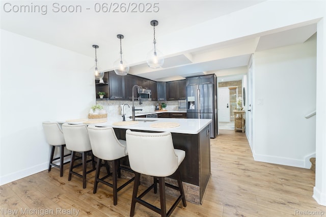 2226 Bowles St, Fenton, MI 48430 - kitchen with stainless steel fridge, a peninsula, backsplash, light countertops, and a breakfast bar