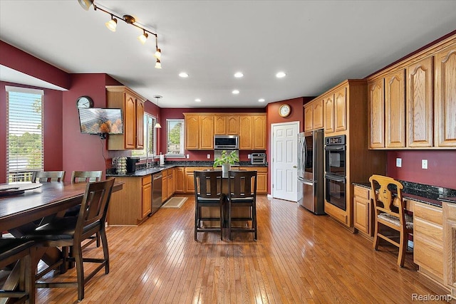 5390 Plantation Dr, Commerce Twp, MI 48382 - kitchen featuring appliances with stainless steel finishes, dark countertops, light wood-style flooring, a kitchen island, and recessed lighting
