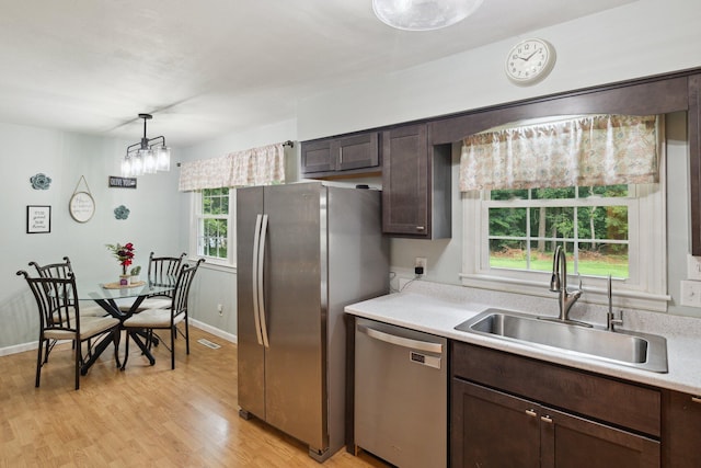 70838 Ridgewood Dr, Edwardsburg, MI 49112 - kitchen with appliances with stainless steel finishes, dark brown cabinetry, light countertops, light wood finished floors, and decorative light fixtures