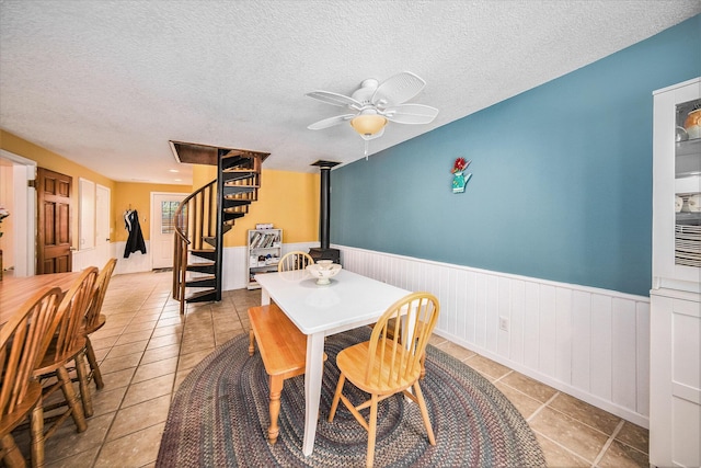 13674 Lenore Dr, Hudson, MI 49247 - dining area featuring stairway, light tile patterned flooring, wainscoting, ceiling fan, and a textured ceiling