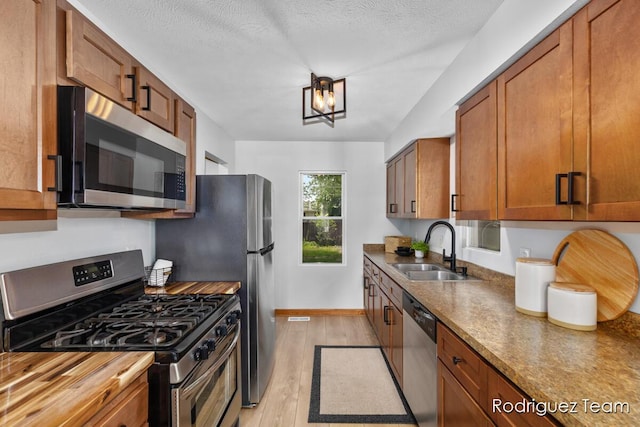 1235 Aurora Ave, Muskegon, MI 49442 - kitchen with appliances with stainless steel finishes, light wood finished floors, brown cabinets, and a textured ceiling