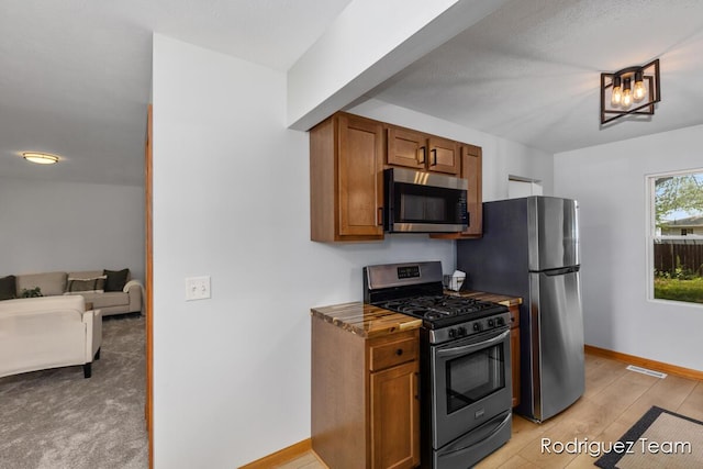 1235 Aurora Ave, Muskegon, MI 49442 - kitchen featuring appliances with stainless steel finishes, brown cabinetry, and light wood-style floors