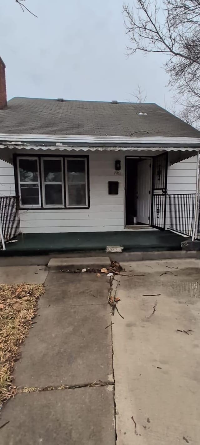 7761 Artesian St, Detroit, MI 48228 - view of front of house with a chimney, a porch, and roof with shingles