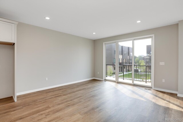 1058 Hampton Cir Unit 74, Detroit, MI 48207 - unfurnished bedroom with access to exterior, light wood-type flooring, and recessed lighting