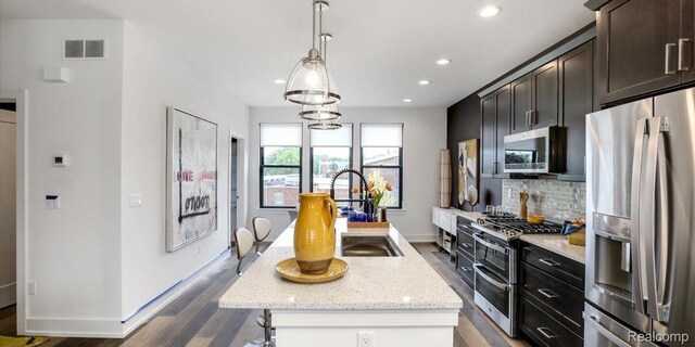 1058 Hampton Cir Unit 74, Detroit, MI 48207 - kitchen with appliances with stainless steel finishes, a kitchen island with sink, backsplash, recessed lighting, and dark wood-style flooring