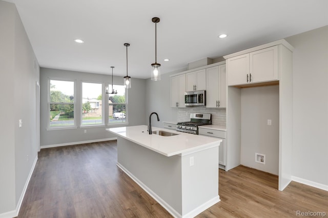1058 Hampton Cir Unit 74, Detroit, MI 48207 - kitchen featuring stainless steel appliances, light wood-type flooring, backsplash, light countertops, and an island with sink