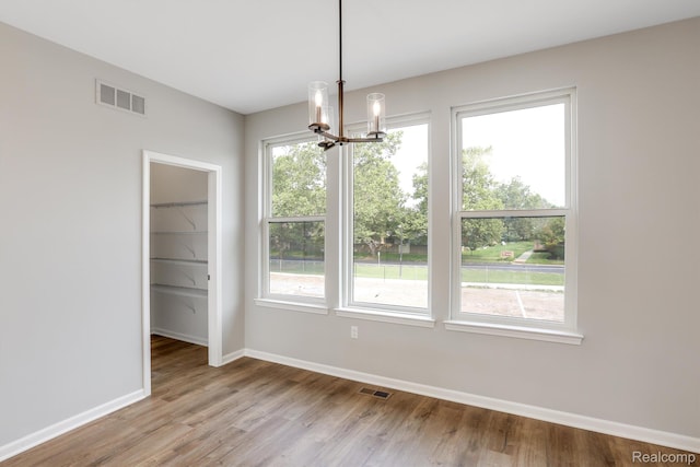 1058 Hampton Cir Unit 74, Detroit, MI 48207 - unfurnished dining area with a chandelier, light wood finished floors, and healthy amount of natural light