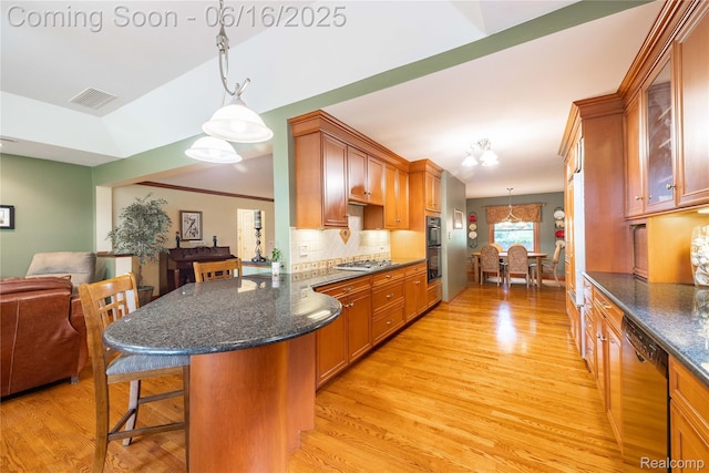 21781 Thorofare Rd, Grosse Ile, MI 48138 - kitchen with appliances with stainless steel finishes, a breakfast bar, light wood-type flooring, and tasteful backsplash
