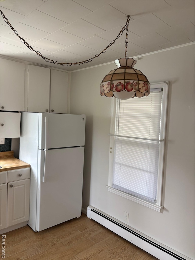 59 W High St, Metamora, MI 48455 - kitchen with baseboard heating, freestanding refrigerator, light wood-style flooring, crown molding, and white cabinets