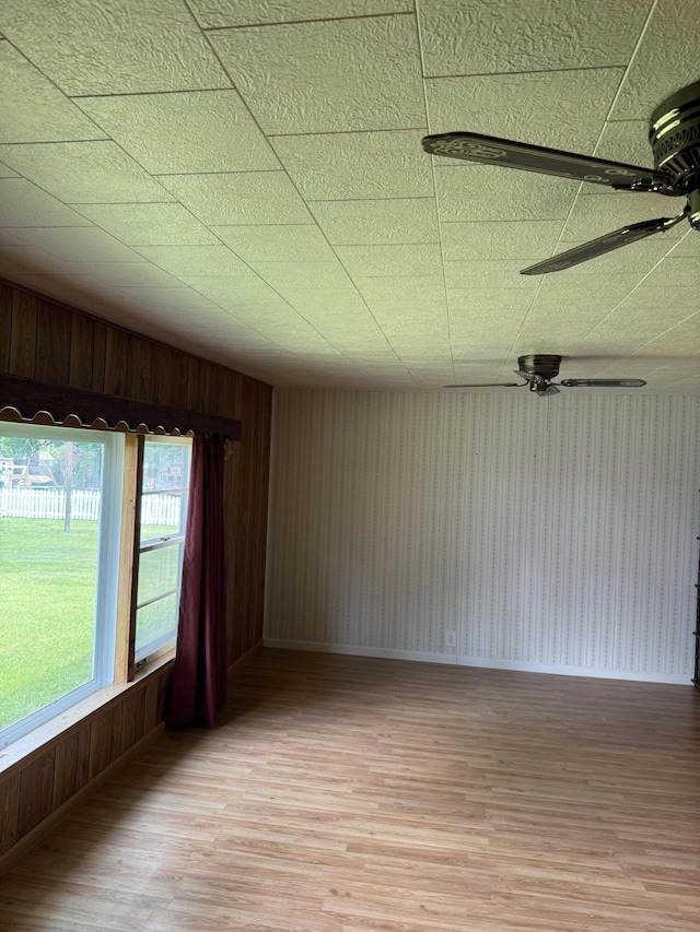 1026 Yeomans St, Ionia, MI 48846 - spare room featuring light wood-type flooring, ceiling fan, and wood walls