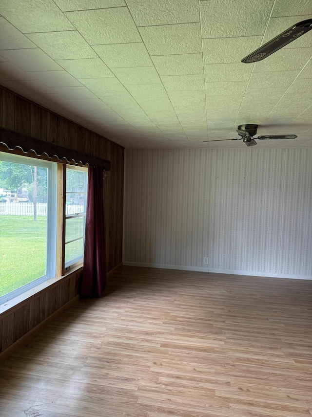 1026 Yeomans St, Ionia, MI 48846 - unfurnished room with light wood-style floors, wood walls, and ceiling fan