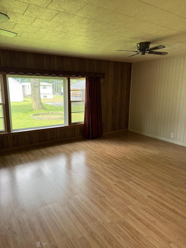 1026 Yeomans St, Ionia, MI 48846 - empty room featuring light wood finished floors, ceiling fan, plenty of natural light, and wooden walls
