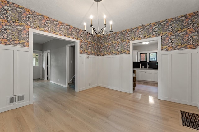 1334 Regent St, Niles, MI 49120 - unfurnished dining area with wallpapered walls, wainscoting, a decorative wall, a chandelier, and a textured ceiling