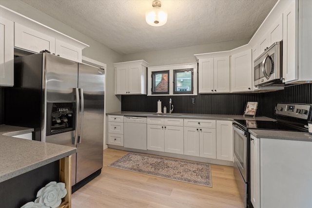 1334 Regent St, Niles, MI 49120 - kitchen featuring appliances with stainless steel finishes, white cabinets, light wood-type flooring, and a textured ceiling