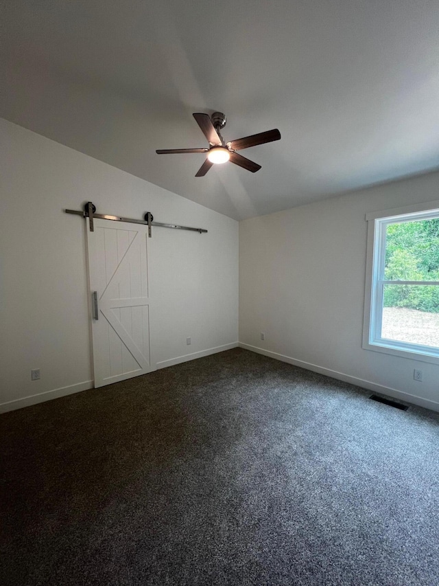 2959 Polaris Ave, Kalamazoo, MI 49004 - unfurnished bedroom with lofted ceiling, a barn door, dark carpet, and ceiling fan