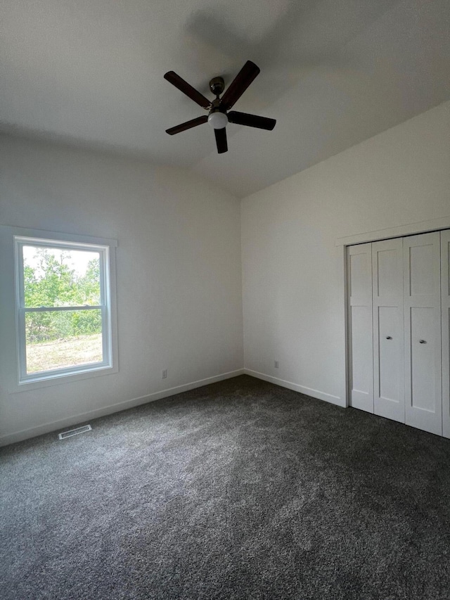 2959 Polaris Ave, Kalamazoo, MI 49004 - unfurnished bedroom with vaulted ceiling, dark carpet, a ceiling fan, and a closet