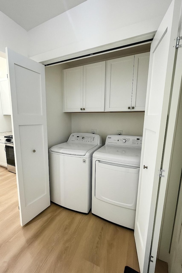 2959 Polaris Ave, Kalamazoo, MI 49004 - laundry area featuring cabinet space, washer and clothes dryer, and light wood-style floors
