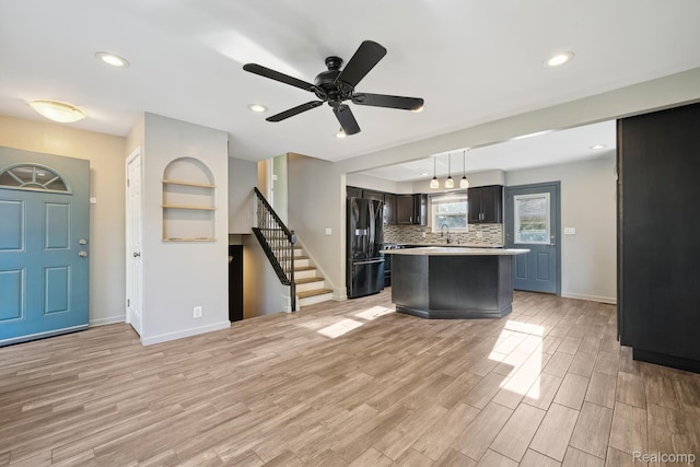 31740 Nelson Dr, Warren, MI 48088 - kitchen with black fridge, light countertops, light wood-type flooring, decorative backsplash, and a center island